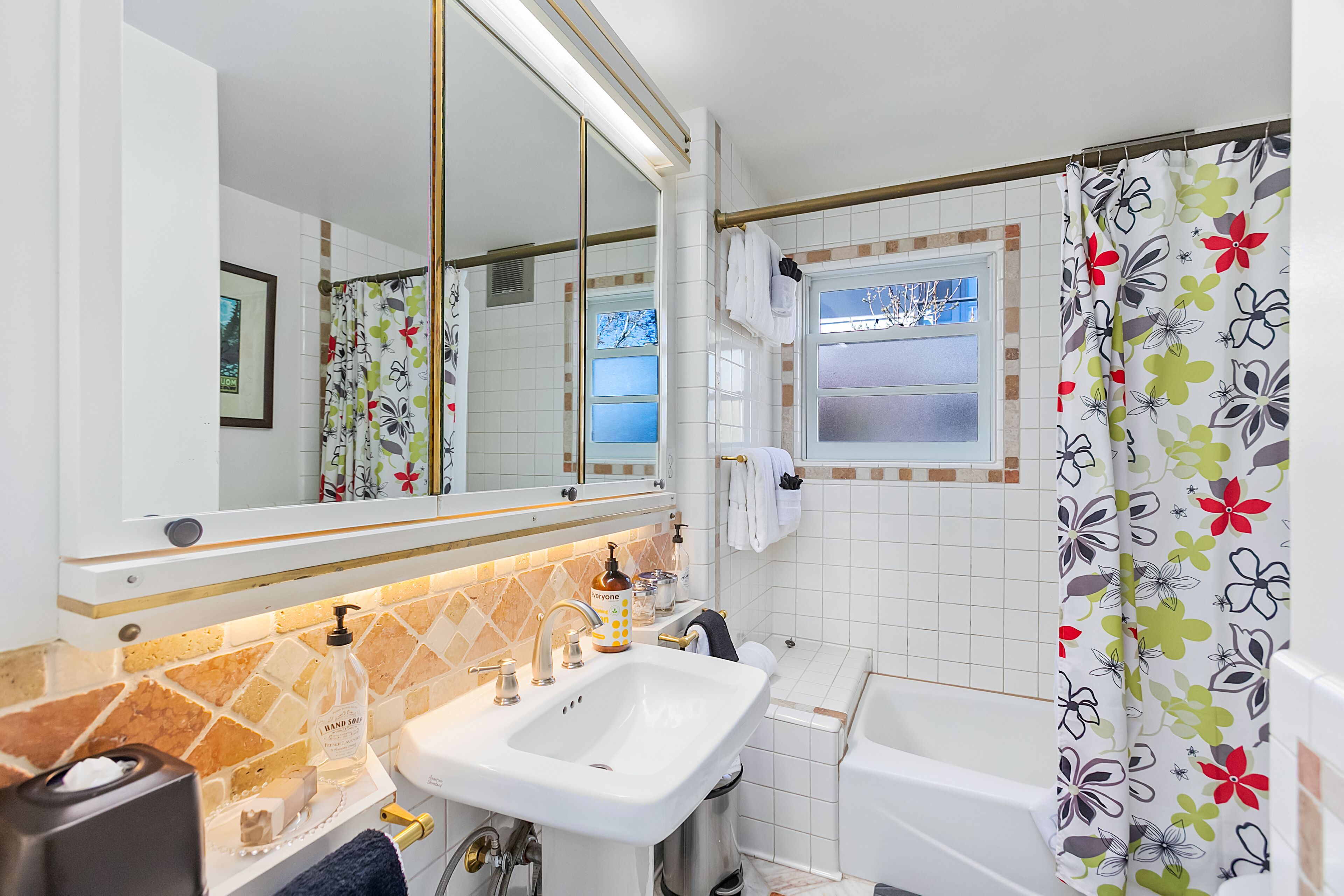 Un baño con lavamanos, espejo y cortina de ducha.