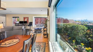 A modern living room with a dining area, large windows, and a view of a cityscape. - Magnolia on the Hill (Seattle)