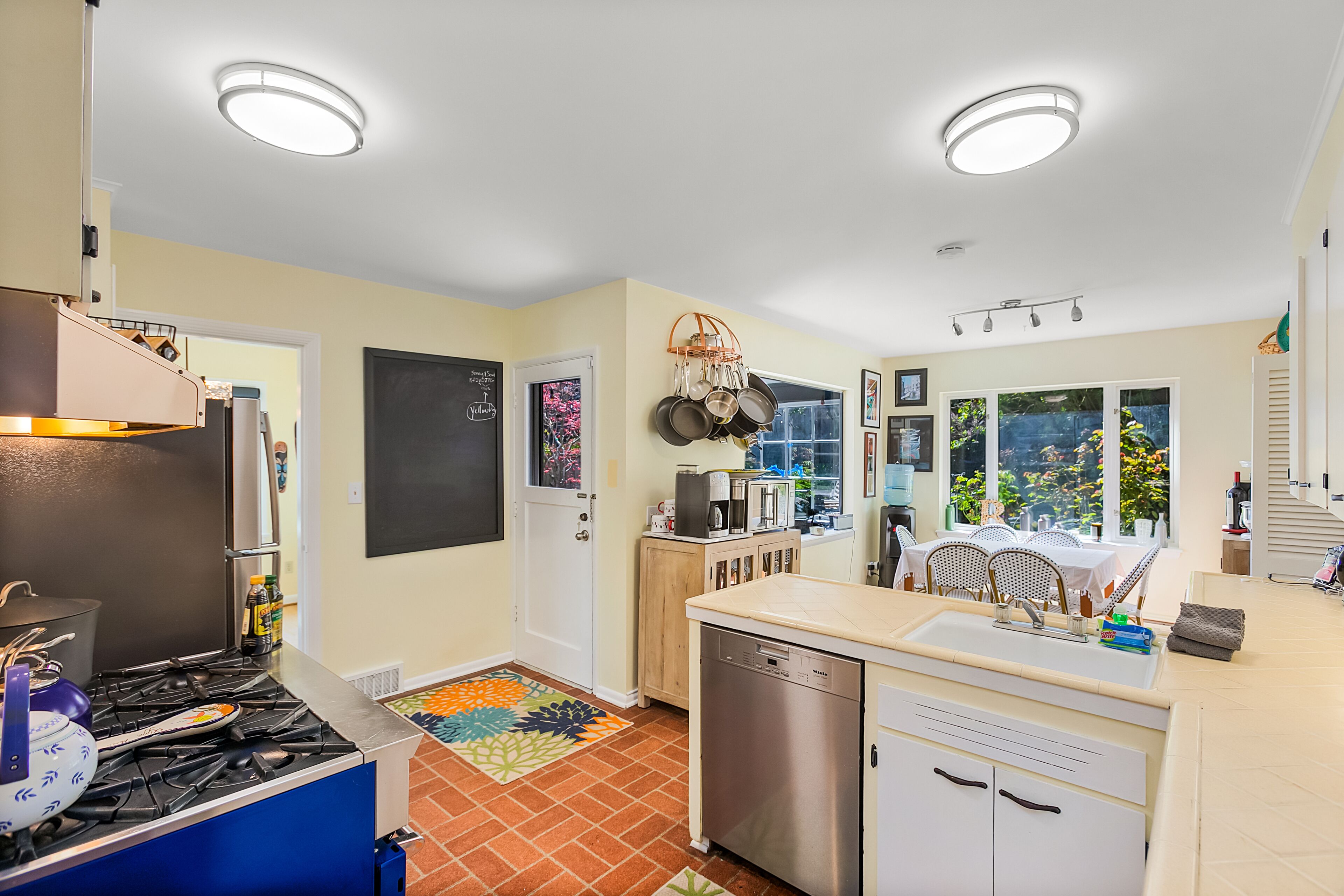 A modern kitchen with a gas stove, dishwasher, and a dining area with a table and chairs.
