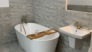 A modern bathroom with a freestanding bathtub, a pedestal sink, and a large mirror. - 1793 Margarethengasse Guesthouse (Sibiu)