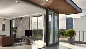 A modern living room with a large TV, a sofa, and a balcony with a view of the city. - Spacious 1bdr Perfect For Romantic Weekend Seaview (Da Nang)