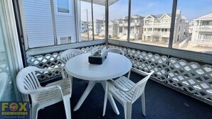 Un espace extérieur abrité, doté d’une table ronde et de quatre chaises, d’où l’on peut admirer une rangée de maisons.