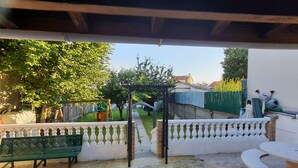 A covered patio area with a bench, a small table, and a pergola. - Grande Maison Familiale Proche Paris /roissy/le Bourget (Le Blanc-Mesnil)