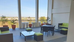 A spacious outdoor patio with wicker furniture, a glass-top table, and potted plants. - Soltana Nature Residence (Lapu-Lapu)