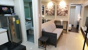 A compact living space with a kitchenette, a sofa, a small table, and artwork on the walls. - Soltana Nature Residence (Lapu-Lapu)