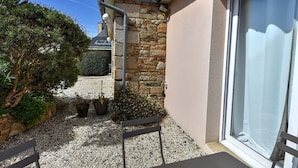 A patio area with a stone wall, a bench, and potted plants. - Les Palmiers D'armor (Penvénan)