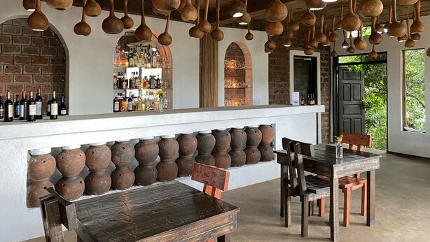 Una zona de bar con muebles de madera rústica, lámparas de barro colgantes y una pared de ladrillo.