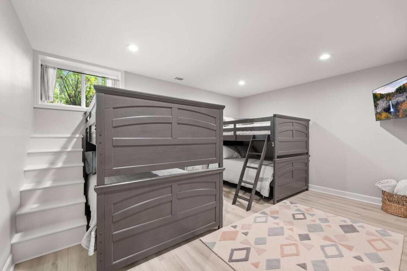 Un dormitorio con dos literas, una ventana, un televisor y una alfombra estampada.
