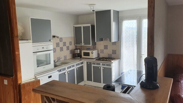 Una cocina compacta con electrodomésticos blancos, armarios grises y salpicadero de azulejos.