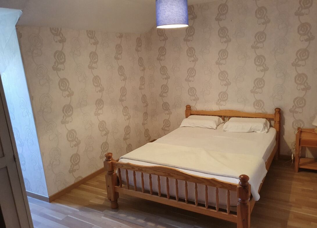 Un dormitorio con una cama de madera, una mesita de noche y un papel tapiz estampado.