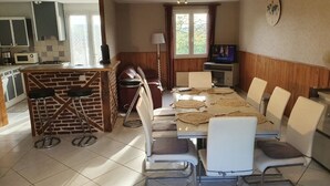 Un comedor con un separador de ladrillo, un televisor y un reloj en la pared.