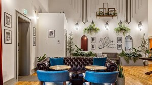 A cozy lounge area with a leather sofa, two blue armchairs, and a wooden coffee table. - Sherlock @The Vestry on Read (Columbia)