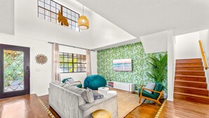Ein modernes Wohnzimmer mit einem grauen Sofa, einem grünen Sessel und einer Holztreppe.