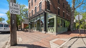 A building with a green facade and large windows, a sign indicating an end school zone, and a brick sidewalk.