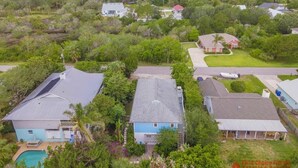 An aerial view of a residential area with houses, a swimming pool, and a large body of water in the background. - Spacious Beach Home - 2 En-suites - Elevator (Saint Augustine)