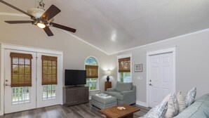 A living room with a ceiling fan, a television, a sofa, a coffee table, and a lamp. - Spacious Beach Home - 2 En-suites - Elevator (Saint Augustine)