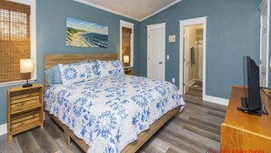 A bedroom with a bed, a ceiling fan, a painting, a door, and a television. - Spacious Beach Home - 2 En-suites - Elevator (Saint Augustine)