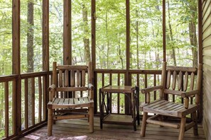 Relax on the deck surrounded by a lush forest, with a view of the natural surroundings.