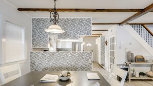 Eine moderne Küche mit weißen Schränken, einer grauen Spritzschutzwand und einem Essbereich mit Tisch und Stühlen.