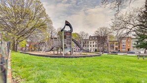 A playground with slides and climbing structures surrounded by a grassy area and trees. - Walk to Downtown Albany: Ten Broeck Triangle Apt! (Albany)