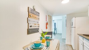 A modern kitchen with white cabinets, a white refrigerator, and a dining area with a table set for two. - Walk to Downtown Albany: Ten Broeck Triangle Apt! (Albany)