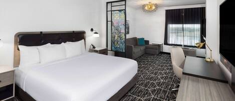 Una habitación de hotel con una cama grande, un escritorio, una silla y un televisor.