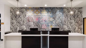 A reception desk with a patterned wall behind it. - La Quinta Inn & Suites by Wyndham Austin Parmer/Tech Ridge (Austin)