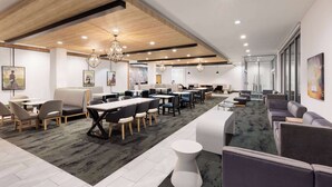 A modern conference room with a wooden ceiling, multiple tables and chairs, and a carpeted floor. - La Quinta Inn & Suites by Wyndham Austin Parmer/Tech Ridge (Austin)