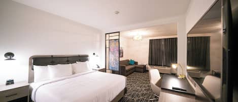 Een hotelkamer met een bed, een bureau, een stoel, een bank, een grote spiegel en een decoratieve wand.