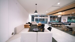 A modern office lounge with sofas, tables, and chairs arranged for seating. - La Quinta Inn & Suites by Wyndham Austin Parmer/Tech Ridge (Austin)