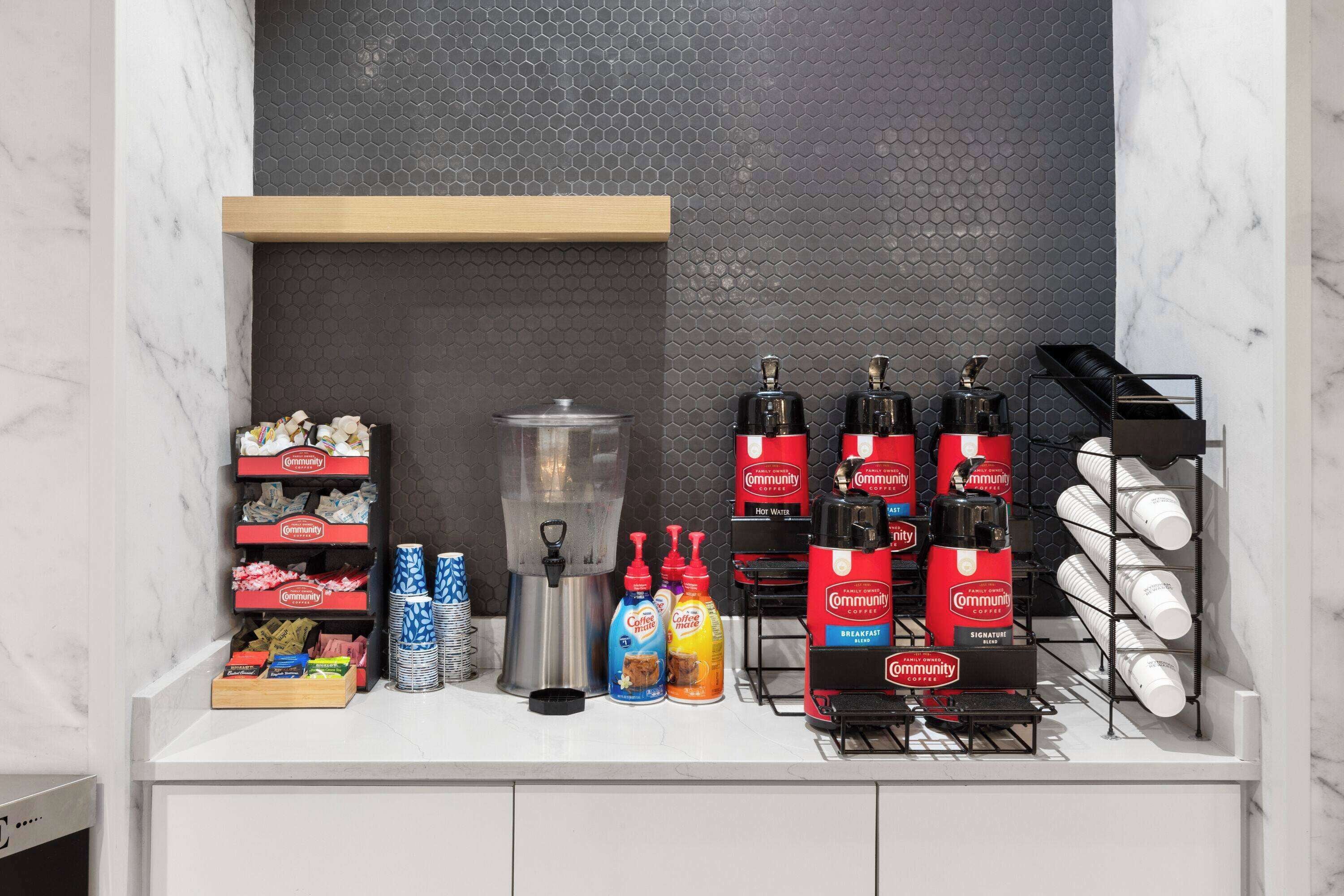 Un comptoir pour le petit-déjeuner, équipé de machines à café, de tasses à café et de divers condiments.
