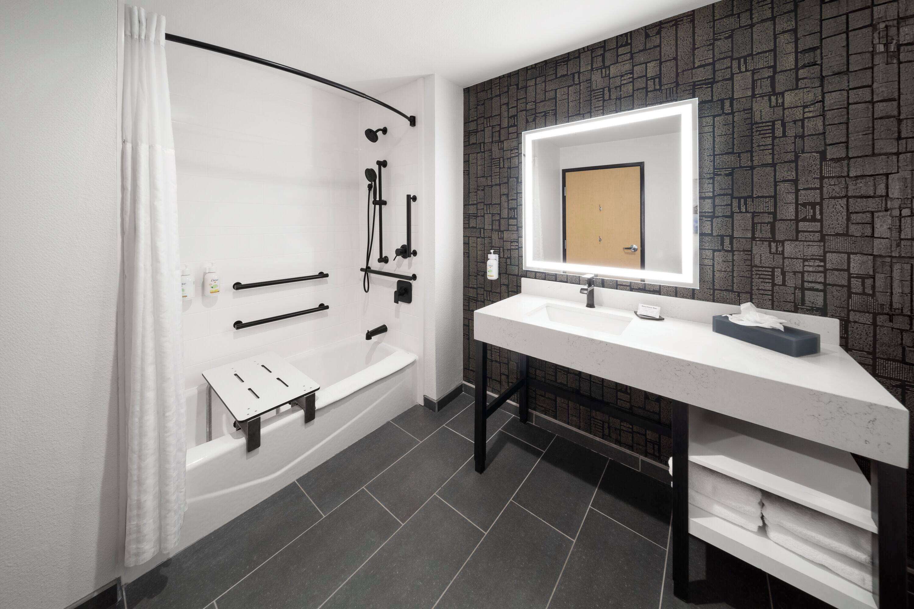 A modern bathroom with a shower, a white sink, and a mirror.