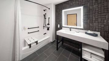 A modern bathroom with a shower, a white sink, and a mirror.