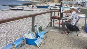 A man painting on a beach with boats and cliffs in the background. - Former presbytery just renovated, 3 stars (Bénarville)