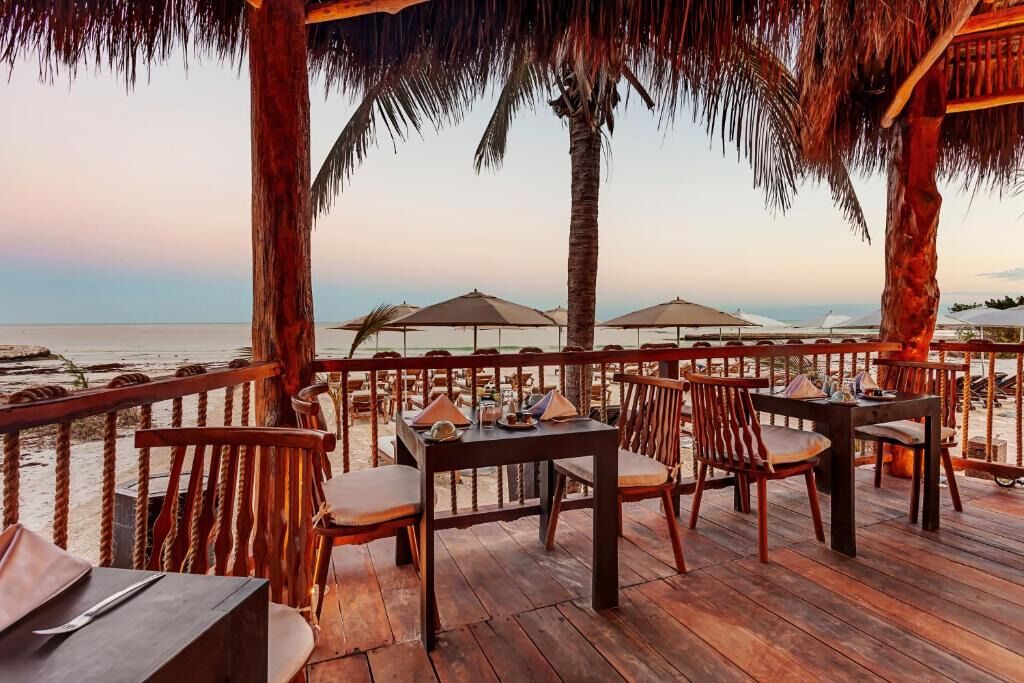 Sip sunset cocktails as the beach glows beyond your table.
