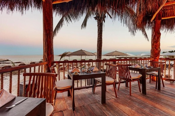 Sip sunset cocktails as the beach glows beyond your table.