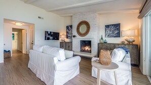 Ein modernes Wohnzimmer mit Kamin, weißen Sofas und einem Fernseher.