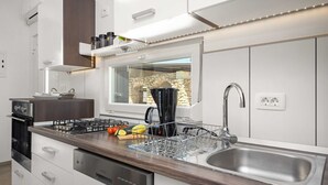 A modern kitchen with a built-in stove, a large sink, and a window overlooking a stone wall. - Villa Marsel (4+2) - Private Pool and Jacuzzi (Gajana)