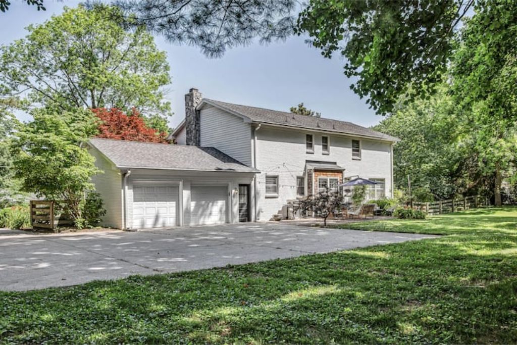 Une maison à deux étages avec un garage, une cour avant et un petit arbre.