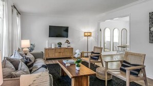 Una sala de estar moderna con un conjunto de sofás, una mesa de centro de madera y un televisor montado en la pared.