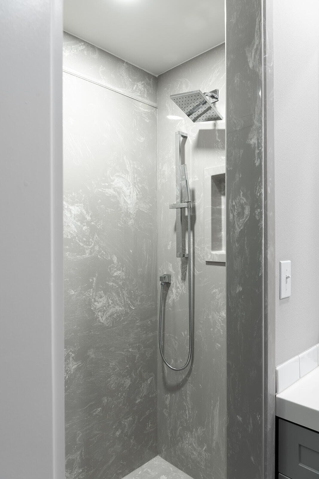Ein Badezimmer mit Dusche, Handtuchhalter und Spiegel.