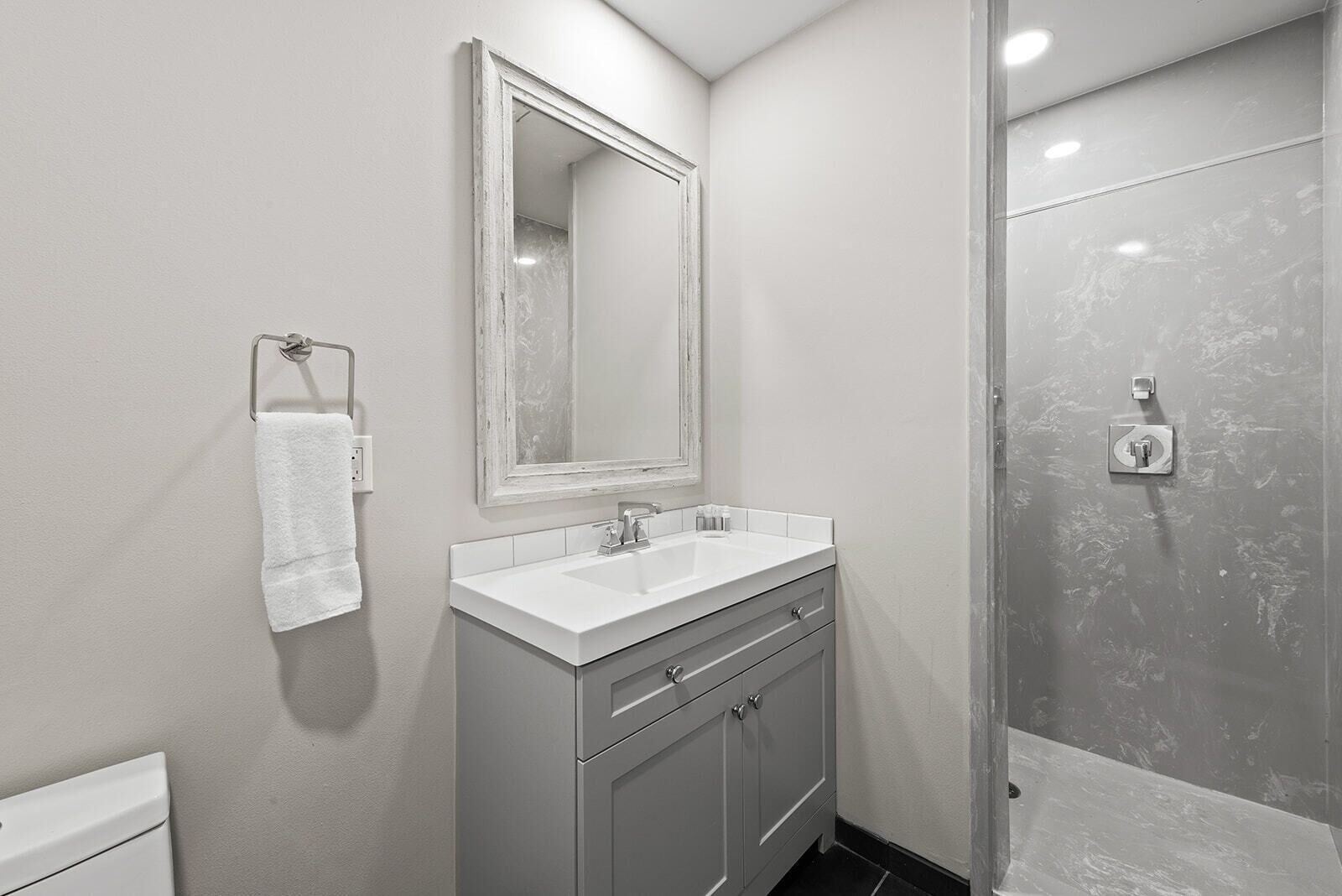 A modern bathroom with a white sink, a mirror, and a shower.