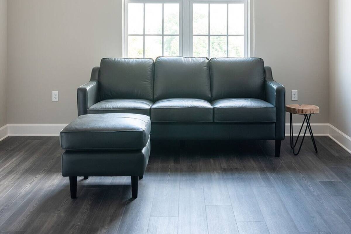 A spacious living room with a sectional sofa, a small ottoman, and a side table.