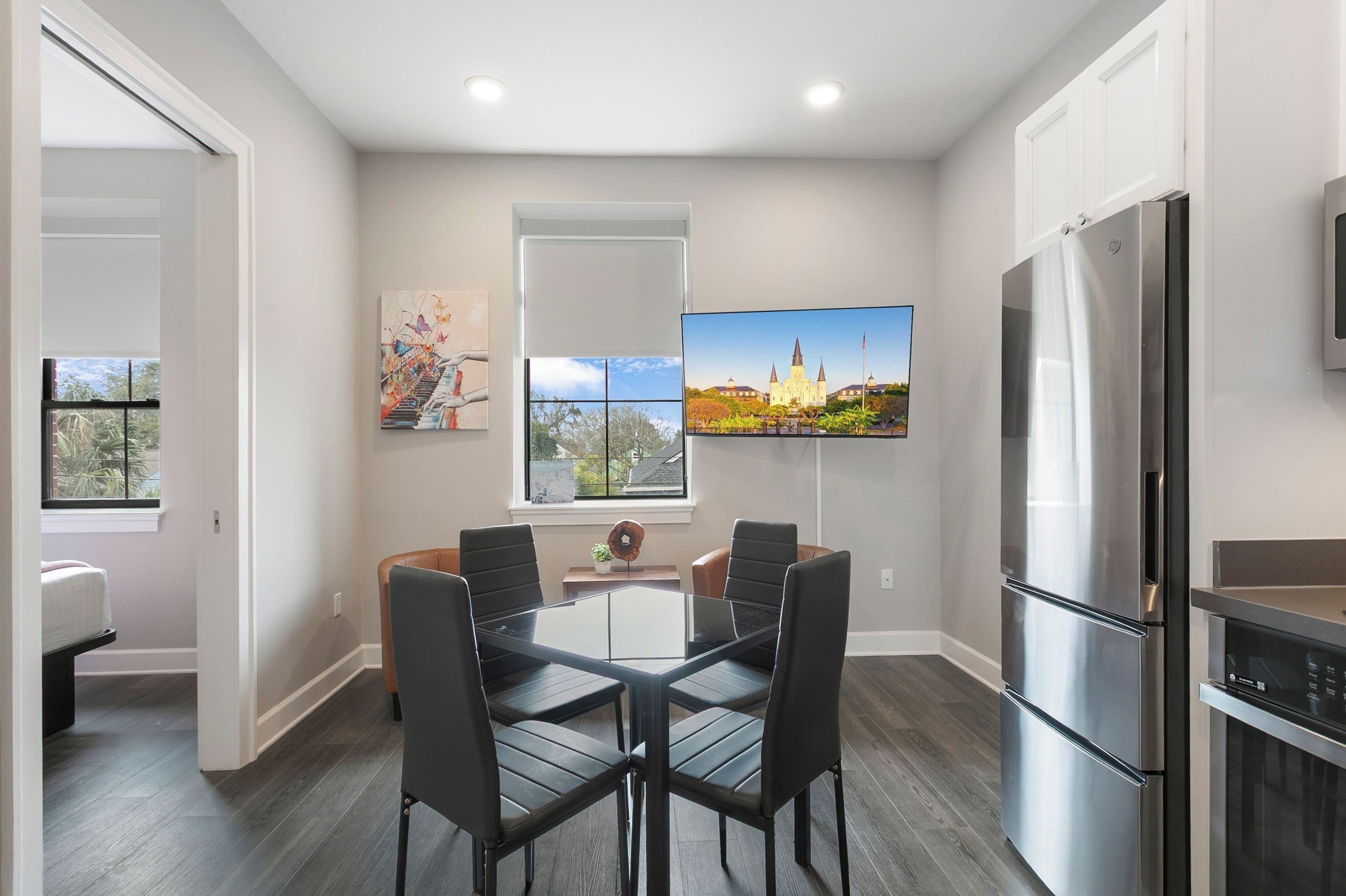 Una cocina moderna con un refrigerador grande, una mesa de comedor con sillas y un televisor de pantalla plana montado en la pared.
