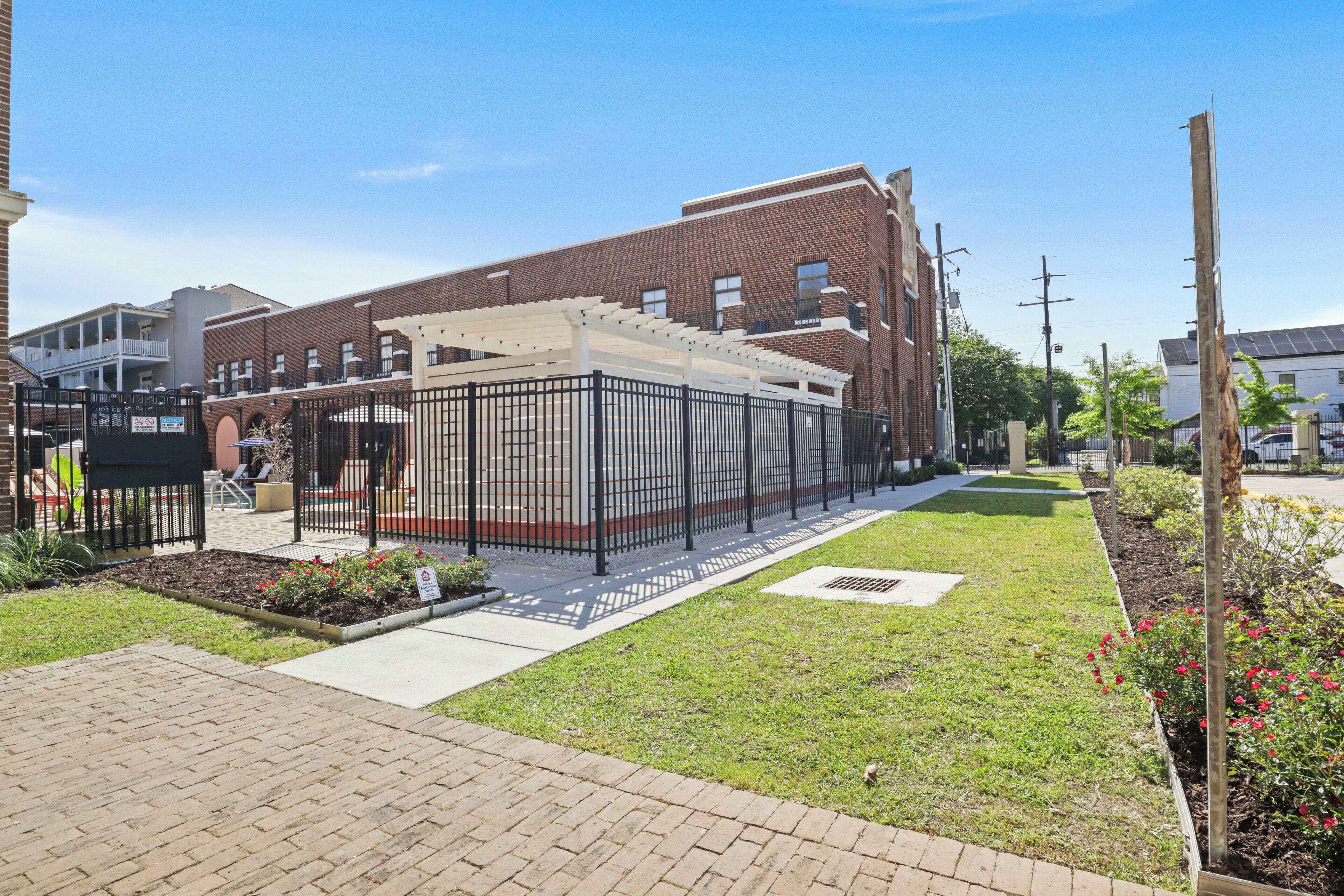 A courtyard with a brick building, a covered seating area, and a small garden.