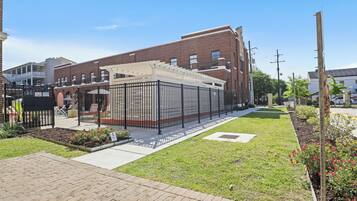 A courtyard with a brick building, a covered seating area, and a small garden.