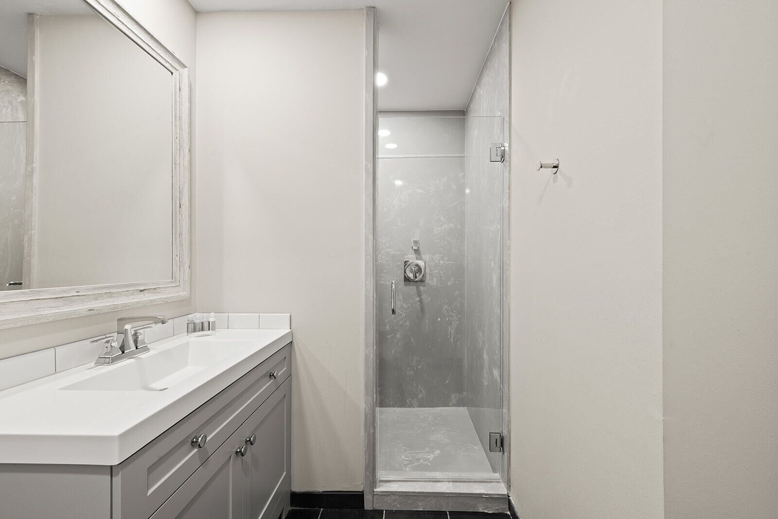 A modern bathroom with a large mirror, a sink, and a shower.