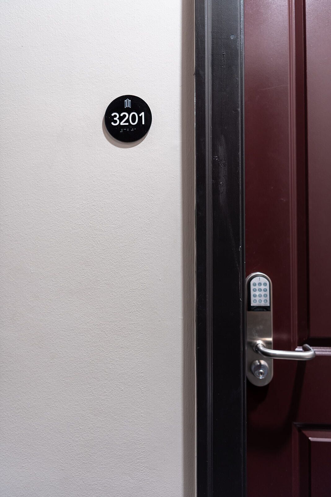 A door with a numeric keypad lock and a black circular sign displaying the number 3201.