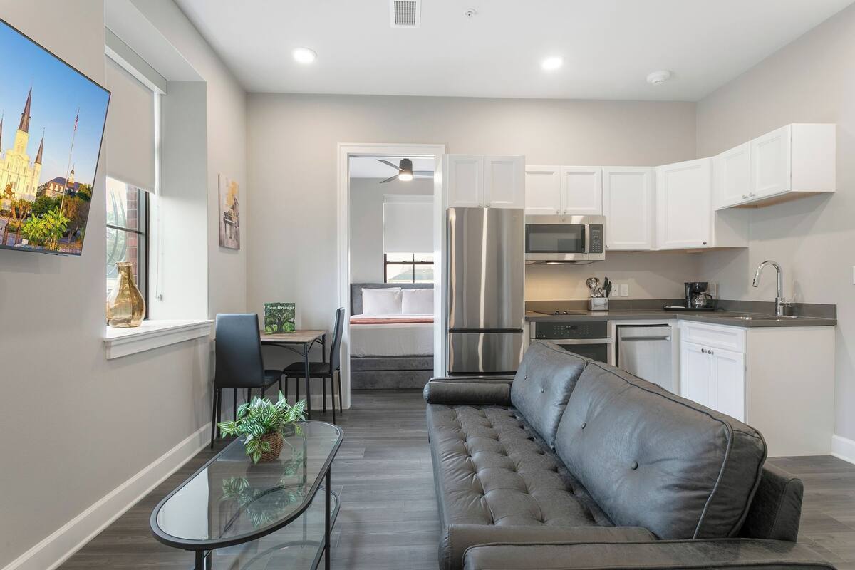 A modern kitchen with white cabinets, stainless steel appliances, and a dining area with a glass table and black chairs.
