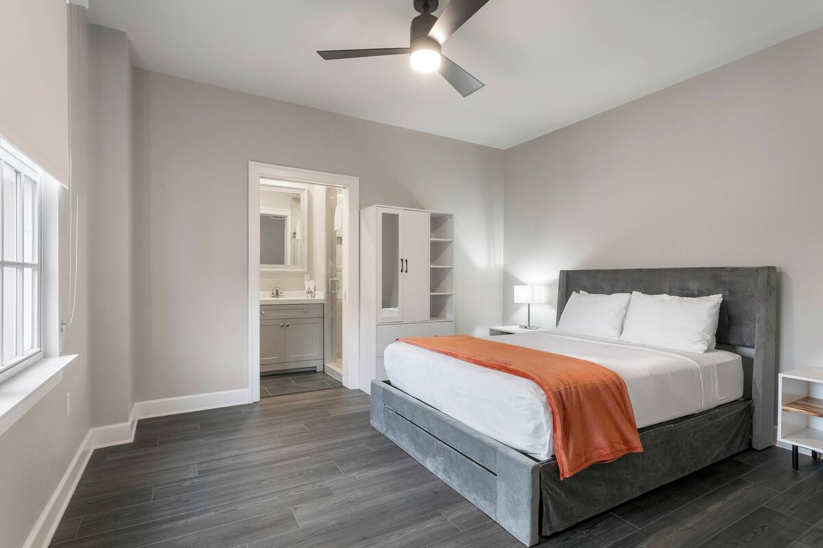 A bedroom with a bed, a ceiling fan, a nightstand, and a walk-in closet.